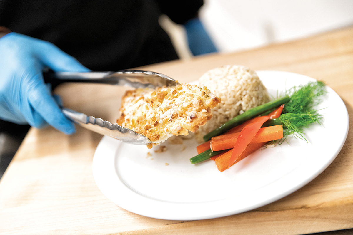 someone putting food on plate with tongs