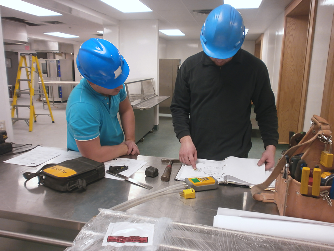 Two men with hard hats reviewing paperwork