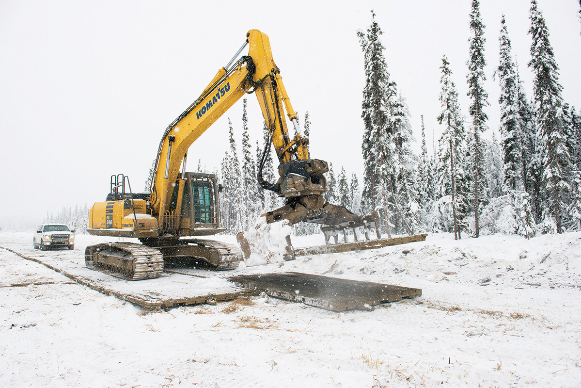 Excavator installing access matting with pickup truck following